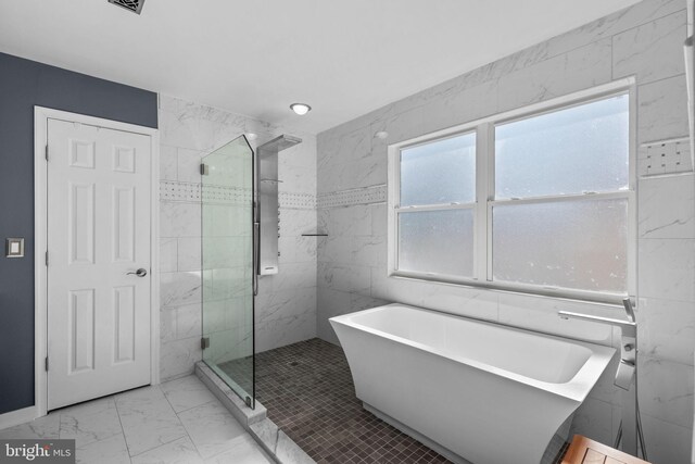 bathroom featuring a soaking tub, a shower stall, tile walls, and marble finish floor