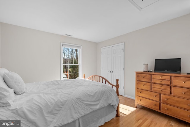 bedroom featuring a closet, visible vents, light wood-type flooring, and baseboards