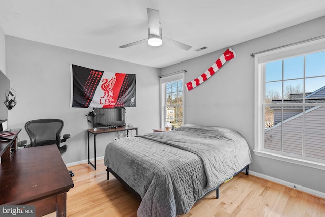 bedroom featuring visible vents, ceiling fan, baseboards, and wood finished floors