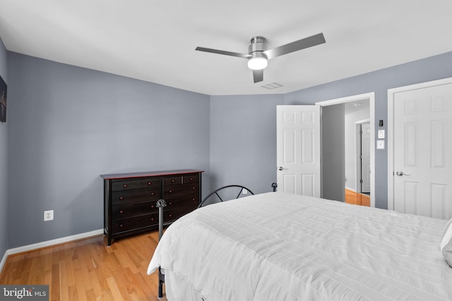 bedroom featuring a ceiling fan, visible vents, light wood-style floors, and baseboards