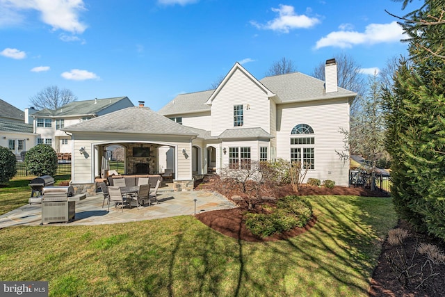 rear view of property featuring a patio area, a yard, a chimney, and fence