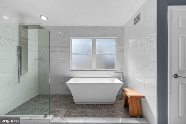 full bathroom featuring tile walls, a freestanding tub, and a walk in shower