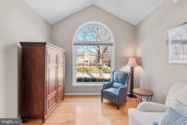 sitting room with baseboards, light wood-style floors, and vaulted ceiling