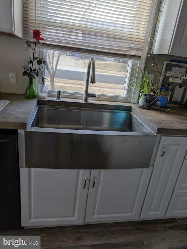 kitchen featuring dark wood-style floors, white cabinets, black dishwasher, and a sink