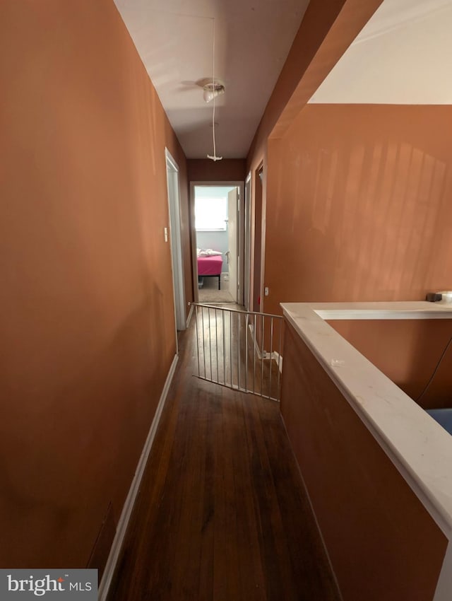 hall featuring dark wood-style floors, an upstairs landing, attic access, and baseboards