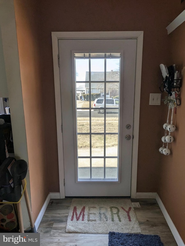 doorway featuring plenty of natural light, baseboards, and light wood-style floors