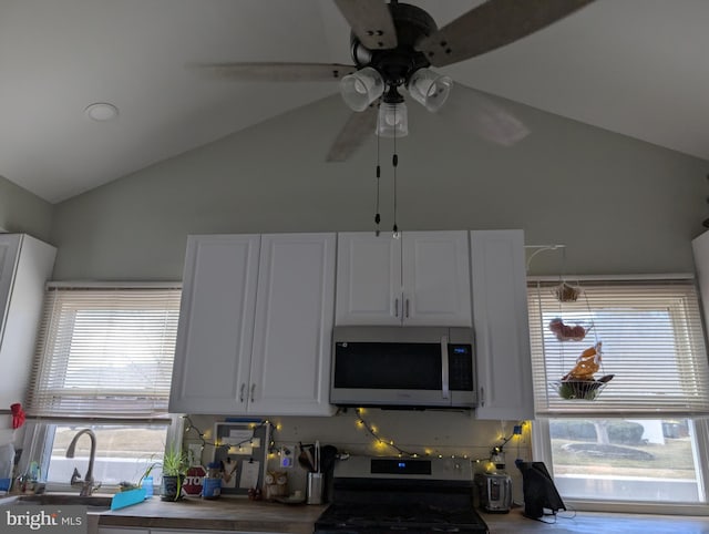 kitchen with a ceiling fan, a sink, vaulted ceiling, appliances with stainless steel finishes, and white cabinetry