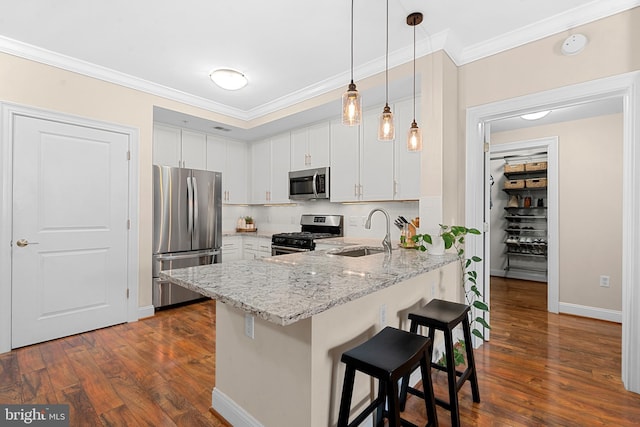 kitchen featuring ornamental molding, a kitchen breakfast bar, a peninsula, stainless steel appliances, and a sink