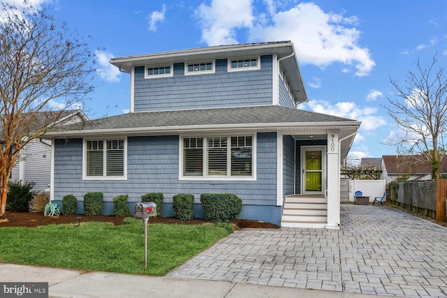 view of front of home featuring a shingled roof, fence, and a front yard