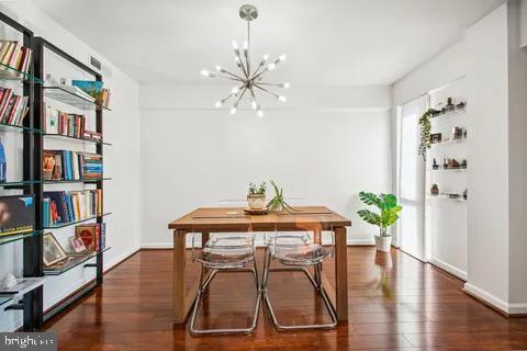 dining space with baseboards, an inviting chandelier, and wood finished floors