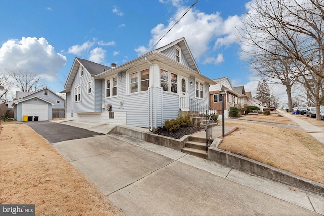 view of front of house featuring aphalt driveway, an outdoor structure, a residential view, and a detached garage