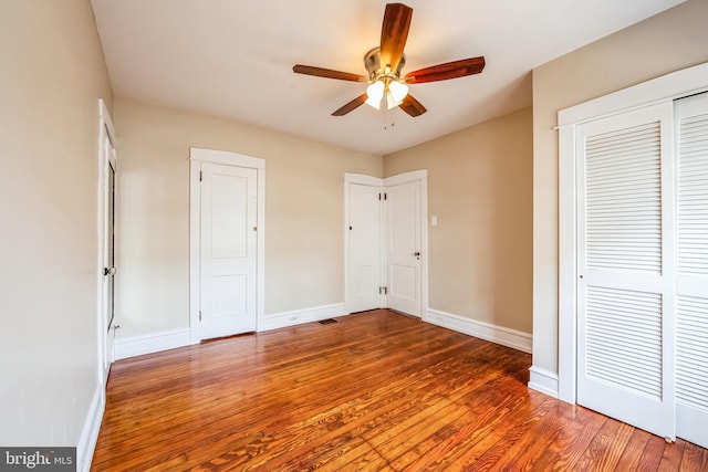 unfurnished bedroom with ceiling fan, wood finished floors, and baseboards