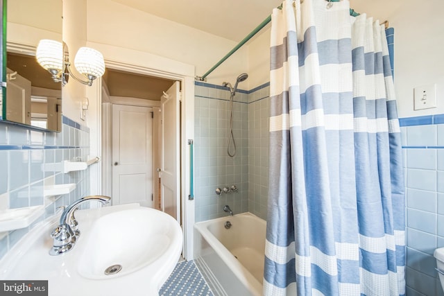 full bath featuring shower / bath combo, tile walls, and a sink