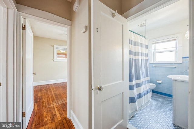 full bath with a shower with curtain, vanity, toilet, and tile walls