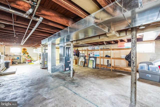 basement with a healthy amount of sunlight, heating unit, and water heater