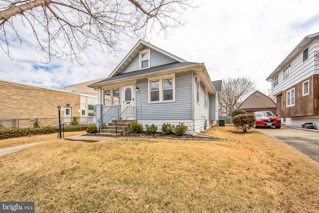 bungalow-style home with a garage, a front lawn, cooling unit, and fence