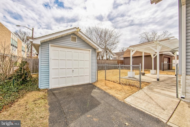 detached garage featuring aphalt driveway and fence