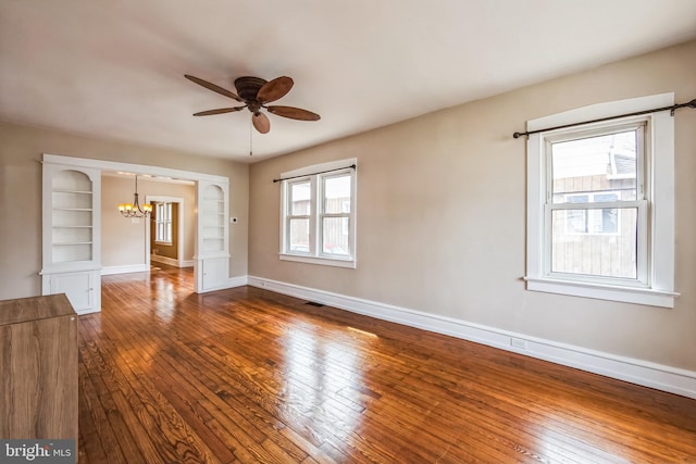 unfurnished room featuring dark wood-type flooring, visible vents, baseboards, and ceiling fan with notable chandelier