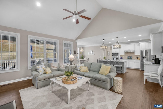 living area featuring visible vents, dark wood-type flooring, high vaulted ceiling, baseboards, and ceiling fan with notable chandelier