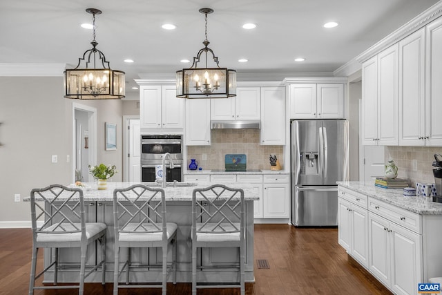 kitchen with dark wood-style flooring, crown molding, appliances with stainless steel finishes, a sink, and under cabinet range hood