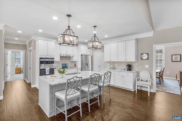 kitchen with white cabinetry, a center island with sink, appliances with stainless steel finishes, and dark wood finished floors