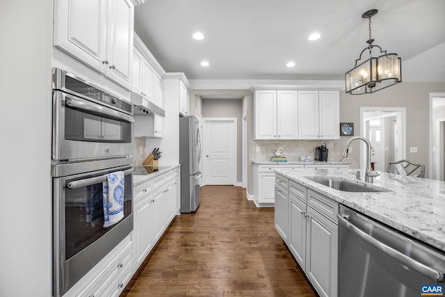 kitchen featuring decorative backsplash, white cabinets, appliances with stainless steel finishes, under cabinet range hood, and a sink