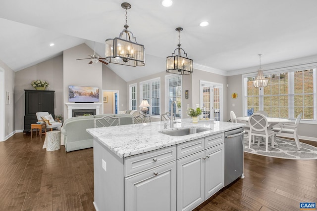 kitchen featuring dark wood finished floors, a fireplace, stainless steel dishwasher, a sink, and an island with sink