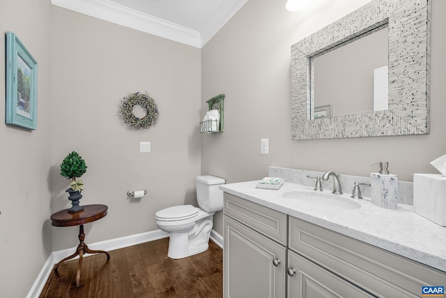 bathroom featuring toilet, wood finished floors, vanity, baseboards, and ornamental molding