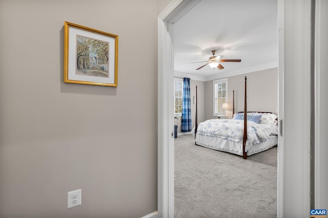 carpeted bedroom with ornamental molding and a ceiling fan