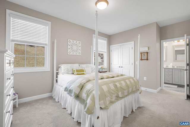 bedroom featuring baseboards, a closet, connected bathroom, and light colored carpet