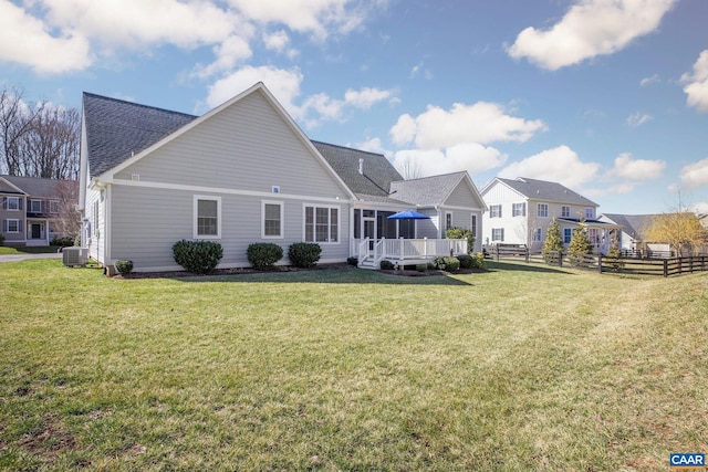 rear view of house featuring a shingled roof, a yard, fence, a wooden deck, and central AC