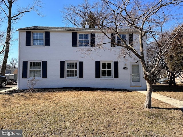 colonial house with a front yard and brick siding