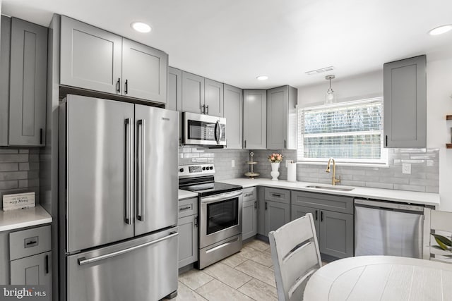 kitchen with stainless steel appliances, gray cabinets, light countertops, and a sink