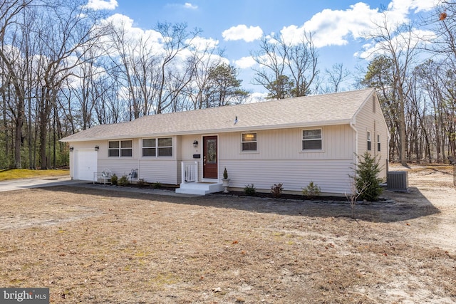 single story home featuring a shingled roof, central AC, and an attached garage