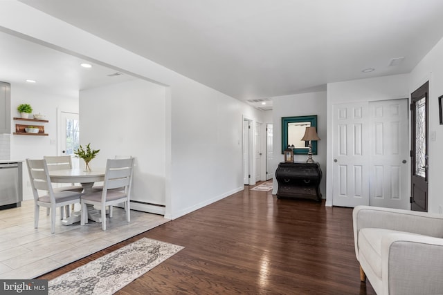 interior space with a baseboard radiator, baseboards, wood finished floors, and recessed lighting