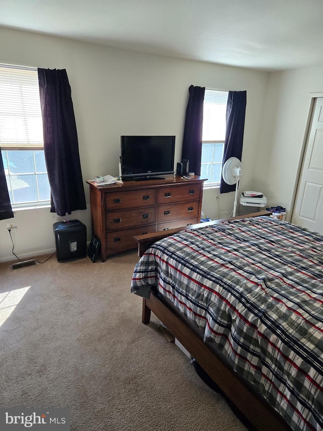 bedroom featuring carpet floors, visible vents, and multiple windows