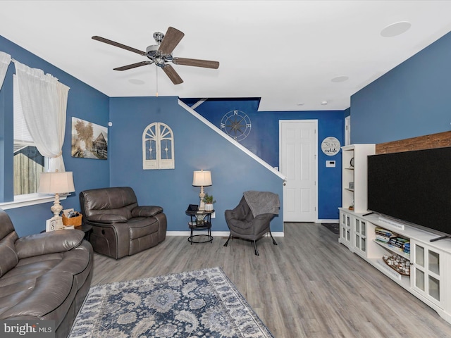 living area with a ceiling fan, baseboards, and wood finished floors