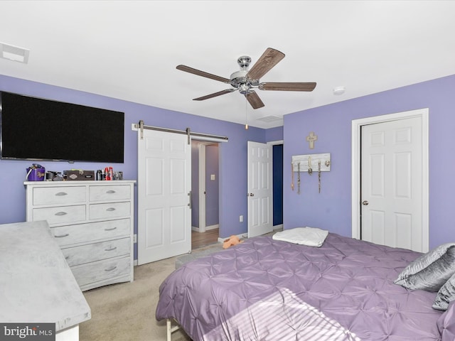 bedroom with a barn door, a ceiling fan, visible vents, and light colored carpet