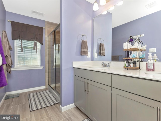 bathroom featuring double vanity, a shower stall, visible vents, and a sink