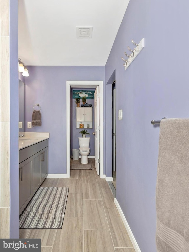 bathroom featuring toilet, baseboards, visible vents, and vanity