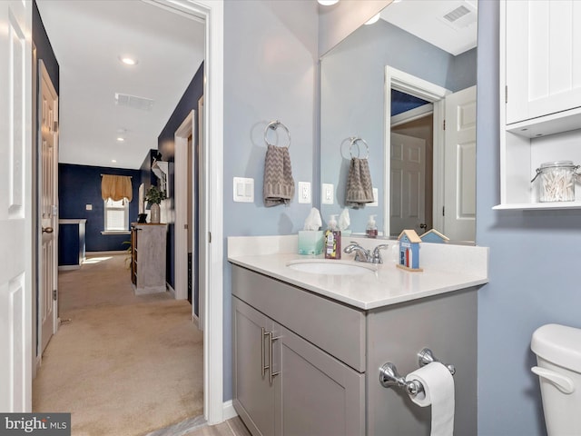 bathroom featuring toilet, vanity, visible vents, and baseboards