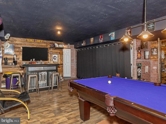 playroom featuring billiards, wood walls, a bar, and wood finished floors