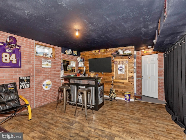 bar with brick wall, a dry bar, and wood finished floors