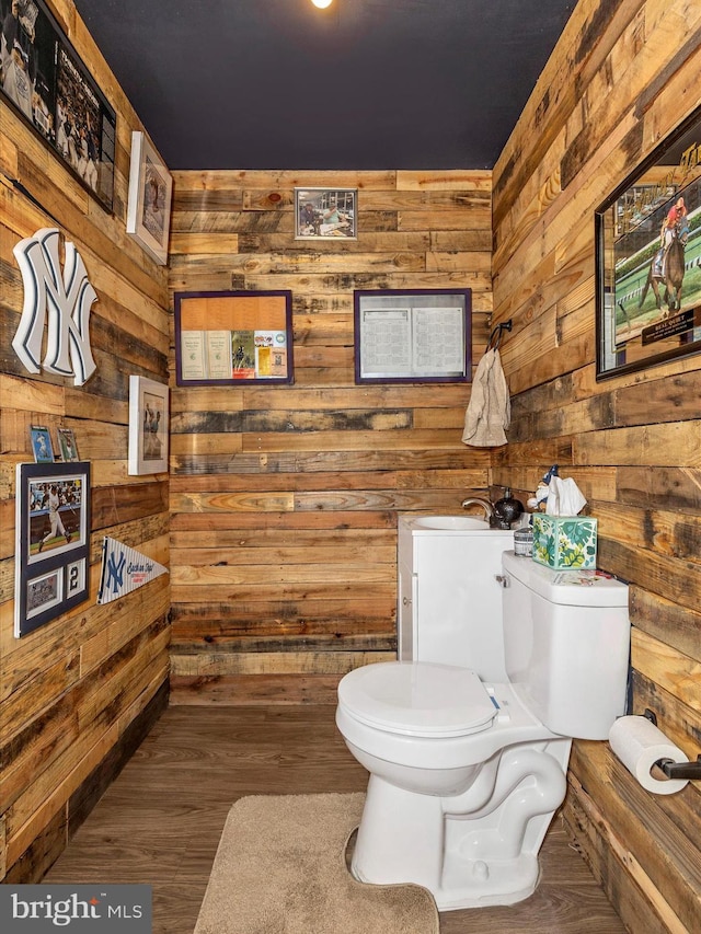 bathroom with wood finished floors, toilet, and wooden walls