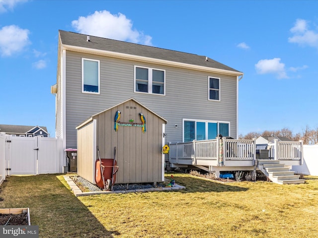 rear view of house featuring a gate, a yard, a deck, and fence