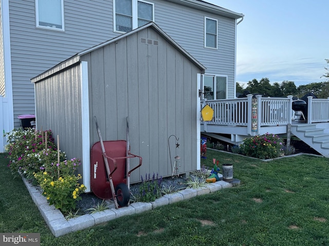 view of side of home with an outbuilding, a lawn, and a wooden deck