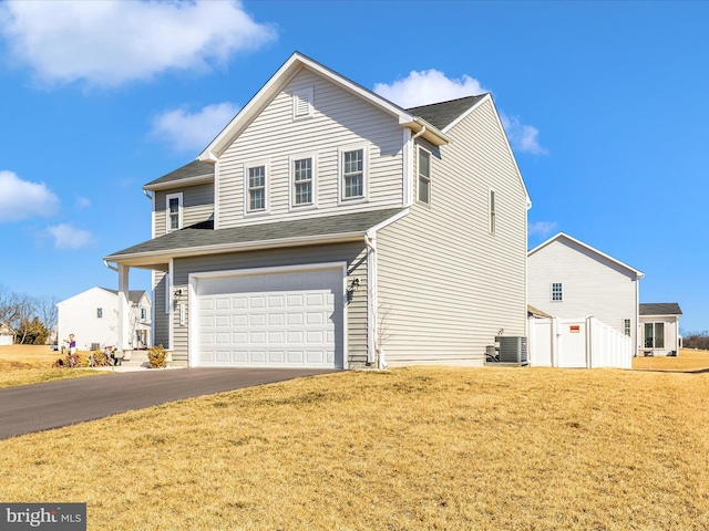 view of front of property featuring aphalt driveway, an attached garage, a front lawn, and central air condition unit