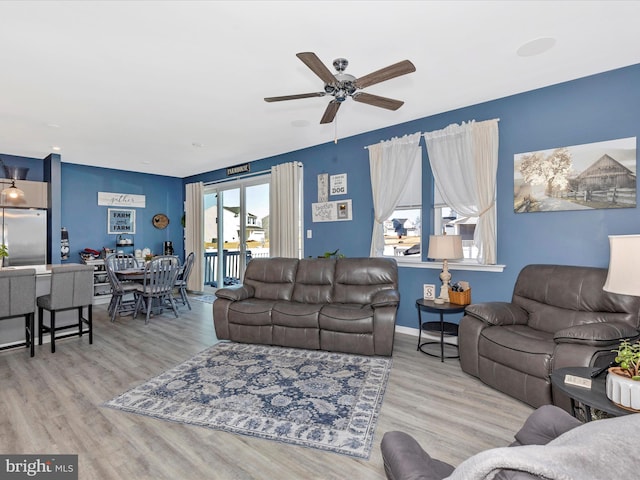 living room featuring a ceiling fan, baseboards, and wood finished floors