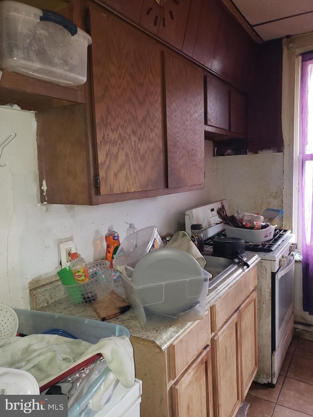 kitchen with light tile patterned flooring, light countertops, and white gas stove