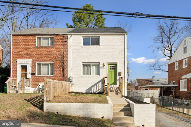 view of front of home with brick siding and fence